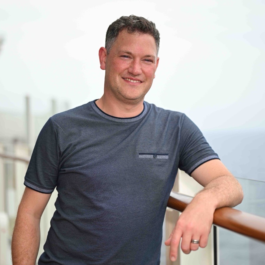 Florian Claus an der Reling eines Kreuzfahrtschiffs, im Hintergrund das Meer
